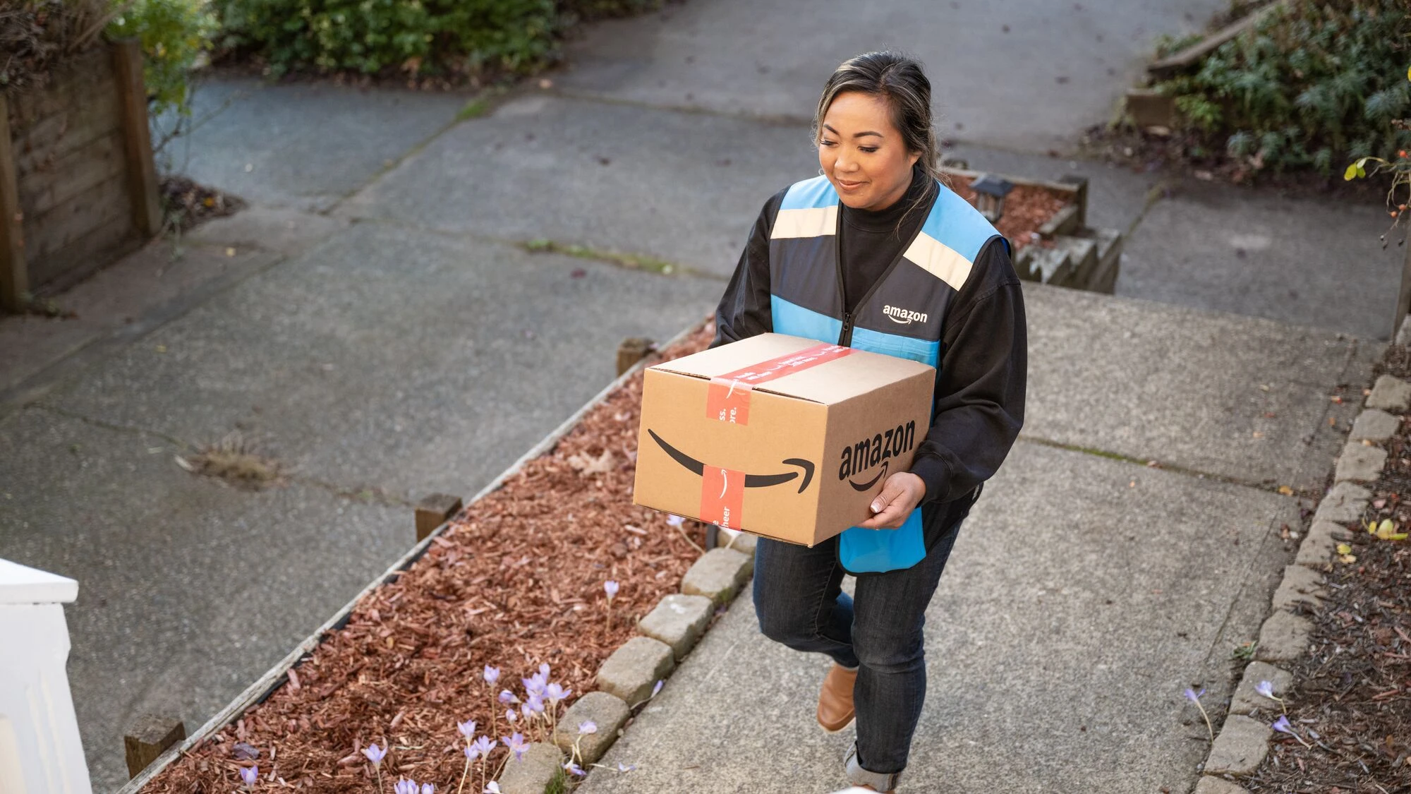 Amazon Flex delivery driver carrying a package to a front door
